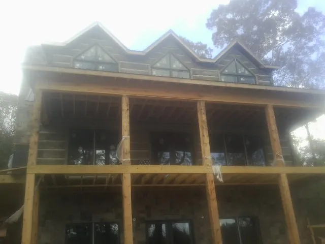 Dormers and porch framing on a large log home under construction — Roof Coating work by our crew in Vancleave